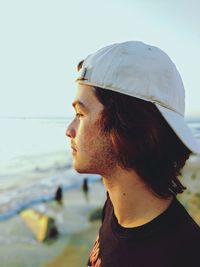 Close-up of young man at beach against sky