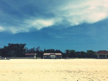 Houses on field by building against sky