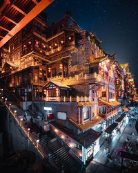 High angle view of illuminated street amidst buildings in city at night