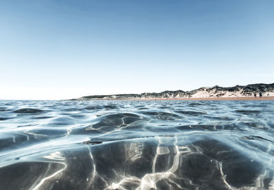 Surface level of sea against clear sky