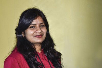 Portrait of smiling woman against wall