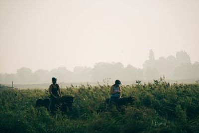 People sitting on field against sky