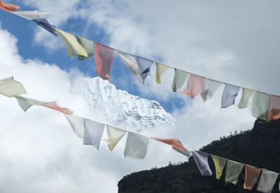 Low angle view of bunting hanging against cloudy sky