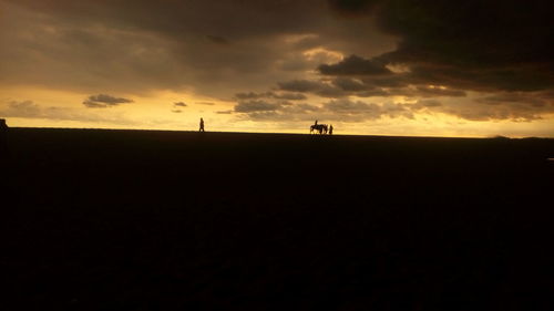 Scenic view of silhouette field against sky during sunset