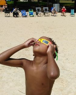 Midsection of shirtless boy on sand at beach