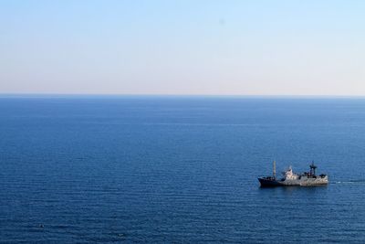 Ship in calm blue sea against clear sky