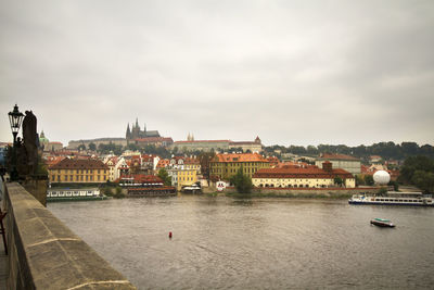 Buildings by river against sky