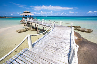 Deck chairs on beach against sky