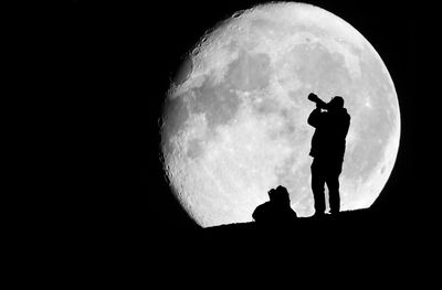 Silhouette men standing against moon at night