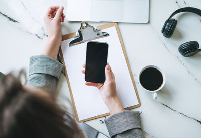  business woman on working place with cup of coffee, notes, smartphone on white marble table 