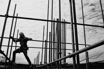 Low angle view of man on suspension bridge against sky