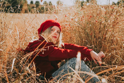 Woman looking away while sitting on field