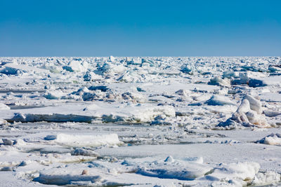 Snow covered landscape against blue sky