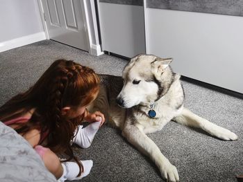 High angle view of woman with dog relaxing on floor at home