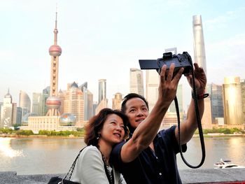 Mature couple taking selfie against skyscrapers