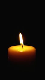 Close-up of lit candle in darkroom