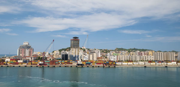 Buildings at waterfront against cloudy sky