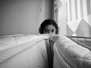 Girl hiding behind mattress