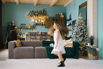 A pretty girl in a white tulle dress and black shoes is spinning in a stylish living room