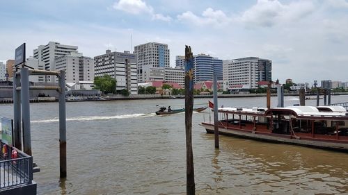 Buildings by river against sky in city