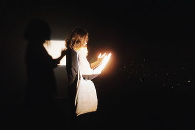 Rear view of woman standing against illuminated lights