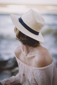 Rear view of woman wearing hat looking at sea