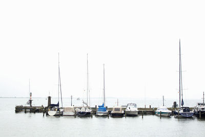 Sailboats moored in sea against clear sky