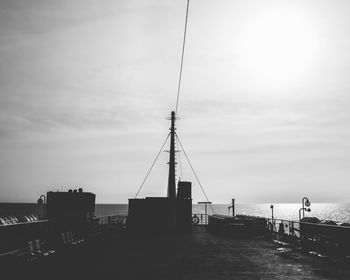 Silhouette pier over sea against sky in city