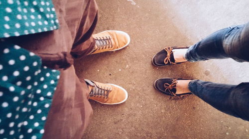 Low section of man and woman wearing shoes standing on street