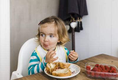 Cute girl having breakfast on table at home