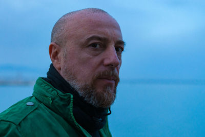 Close-up portrait of mature man standing at beach during sunset