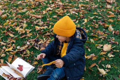 Rear view of boy holding umbrella while sitting on land