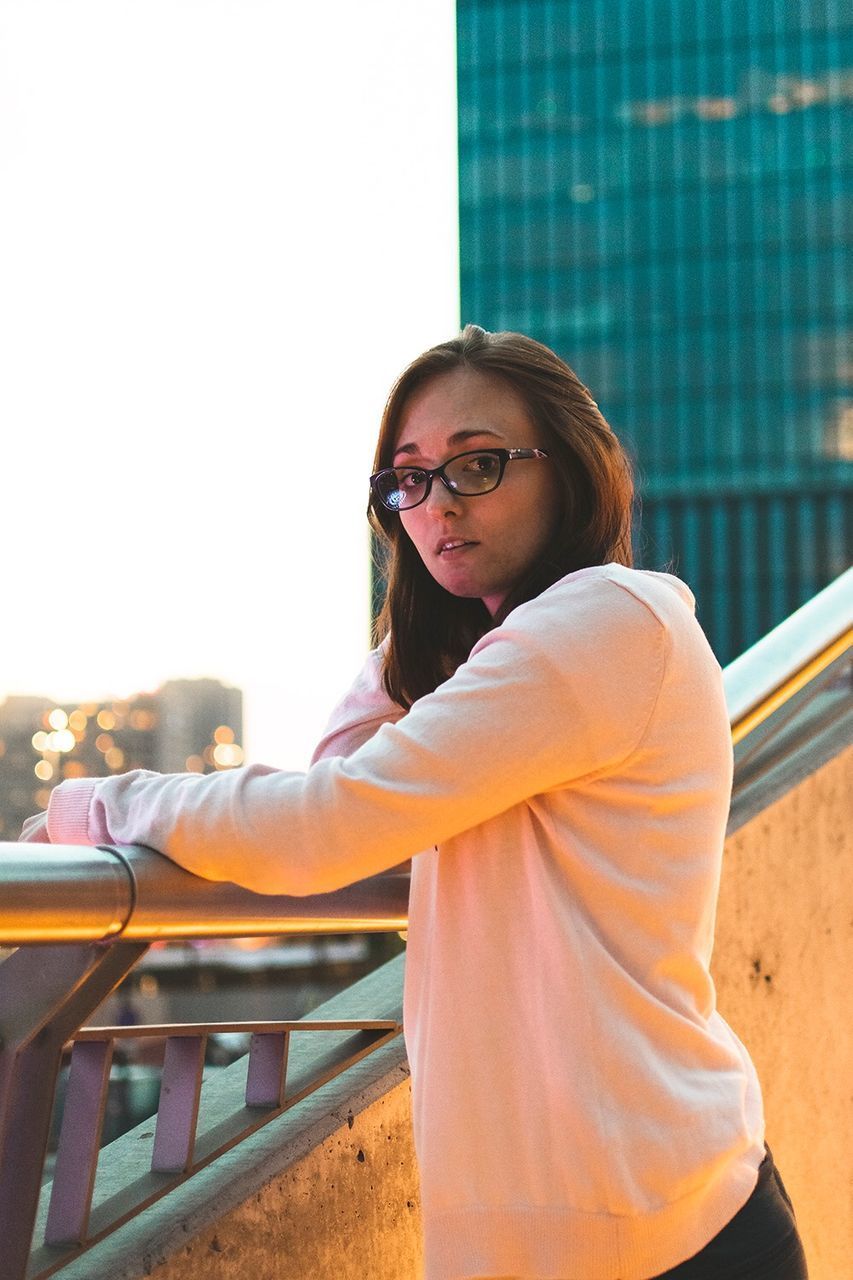 PORTRAIT OF WOMAN STANDING AGAINST RAILING