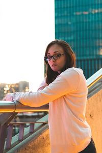 Portrait of smiling woman standing against railing