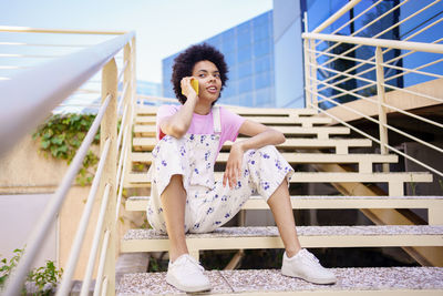 Portrait of young woman standing against railing