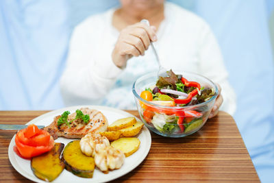 Midsection of man holding food in plate on table