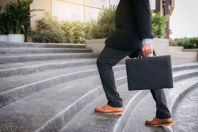 Low section of businessman with briefcase walking on steps