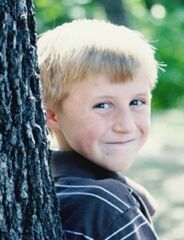 headshot, focus on foreground, close-up, portrait, looking at camera, person, lifestyles, front view, leisure activity, day, head and shoulders, outdoors, human face, childhood, cute, smiling, selective focus, tree trunk