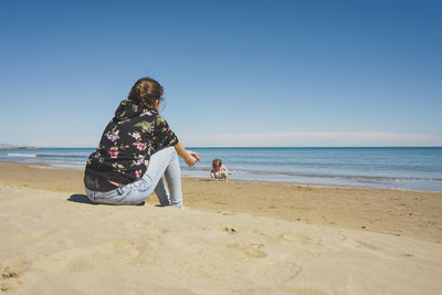 Rear view of woman standing at beach