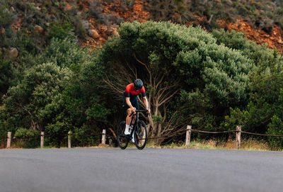 Rear view of man riding bicycle on road