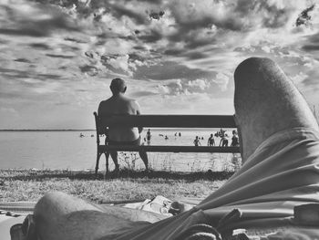 Man sitting on beach against sky