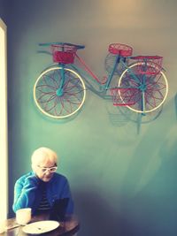 Man with bicycle standing against wall