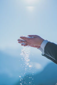 Midsection of man holding umbrella against blue sky