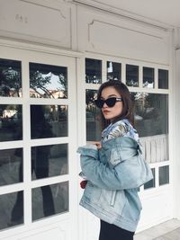 Woman wearing sunglasses while standing against closed door