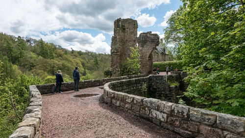 People walking on stone wall against sky