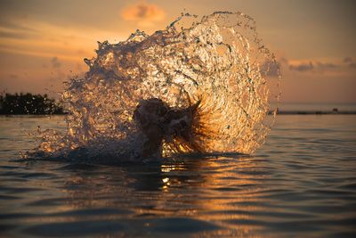 Woman tossing hair in sea during sunset