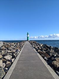 Lighthouse by sea against blue sky