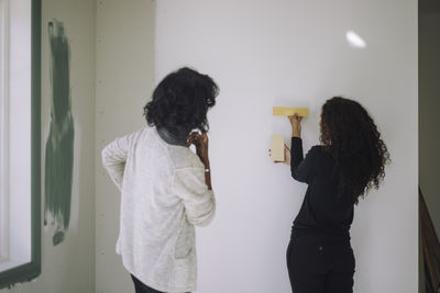 Female architect showing wall paint samples to client while standing at under construction apartment