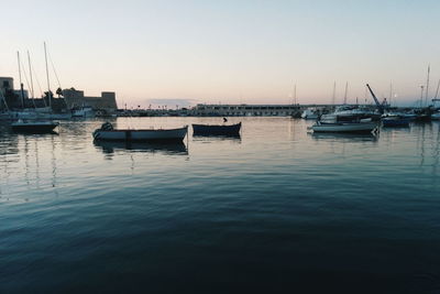 Sailboats moored on river against sky during sunset