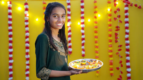 Diwali hindu festival of lights celebration. diya or oil lamp in woman hands with yellow background.